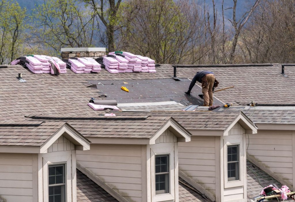 Roofing contractor removing the old tiles before replacing with new shingles on a townhouse roof in Woodbury