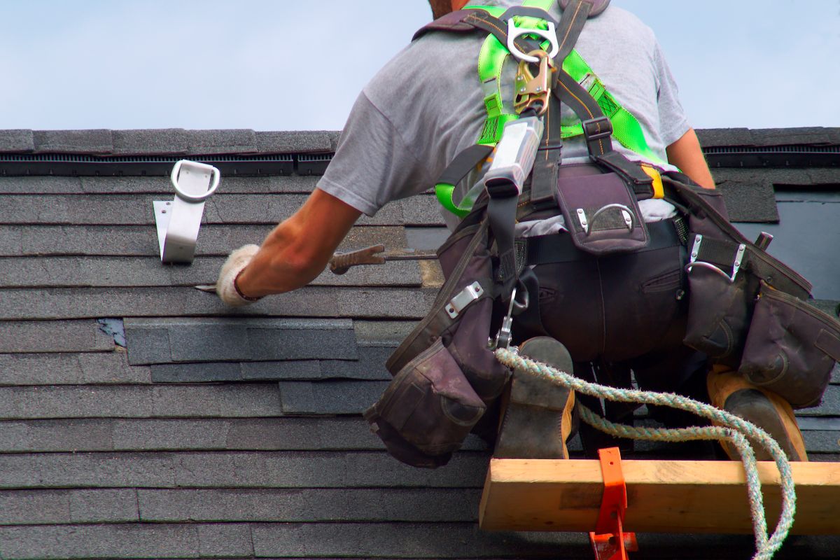 Roofer repairing asphalt shingles on a roof of a Woodbury house